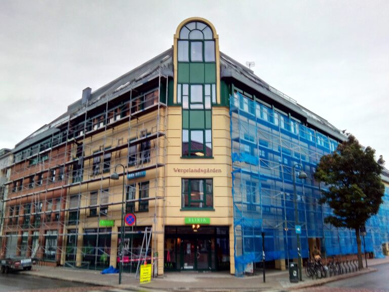 Mitmekorruselise maja fassaad tellingutel, aknaraamide kiletamine musta metallik dekoratiivkilega