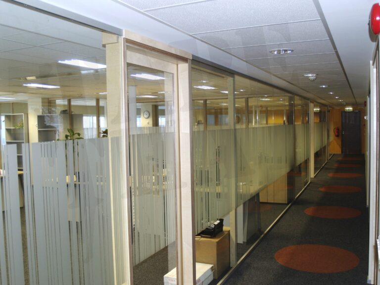 Kontorikoridor klaasist vaheseinte kiletamine, mille alumine osa on kaetud mattide triibuliste privaatsuskiledega